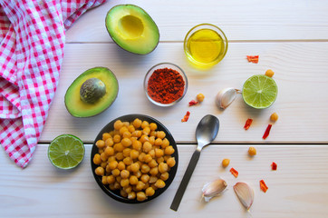 Ingredients for cooking delicious Avocado  hummus. Chickpeas, olive oil, lemon juice, garlic and spices on wooden background. Healthy eating.