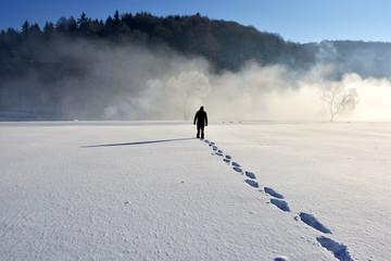 Man walking on snow, footprints in snow, behind - 115231461