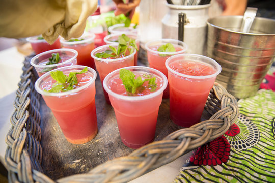 Stall holder garnishing fruit drinks with mint on cooperative food market stall