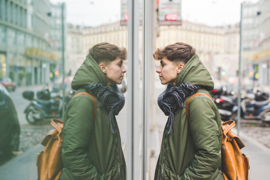Young woman looking at reflection in window, outdoors