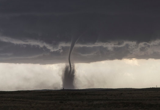  A fine tornado dances within a cloud of dust that moves in ringlets up the lower half of the tornado