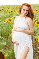 Fototapeta na wymiar Pregnant girl in the field with sunflowers