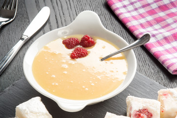 Crema pasticcera con lamponi rossi nel contenitore in ceramica su un tavolo