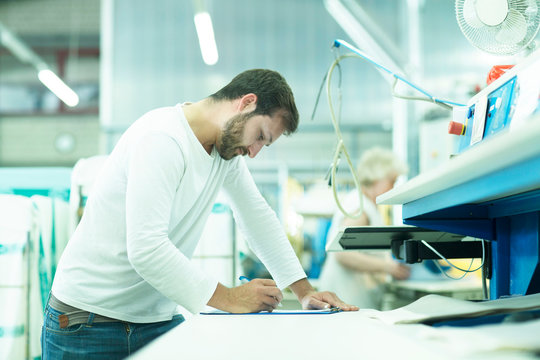 Man working in launderette making notes
