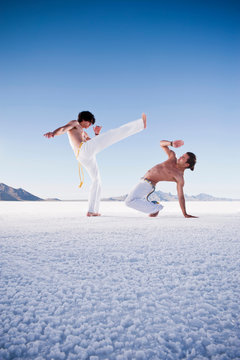 Two men opposite each other performing capoeira on Bonneville Salt Flats, Utah, USA