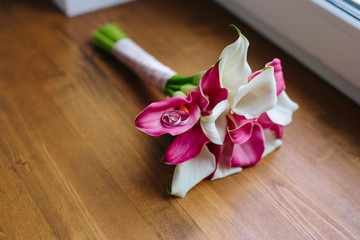 Obraz na płótnie Canvas Wedding rings on bouquet of Calla lilies