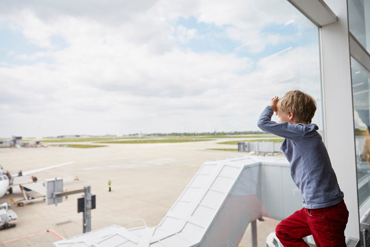 Boy looking out of airport window at runway
