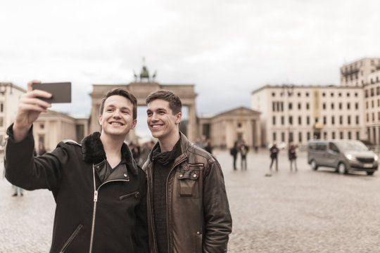 Two teenagers taking a smartphone image of themselves in front of the Brandenburg Gate in Berlin