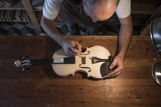Luthier adjusting the sound post of an unvarnished violin in his workshop