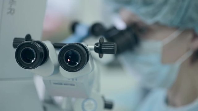 Unrecognizable Doctor looking in microscope during operation. 1080p.