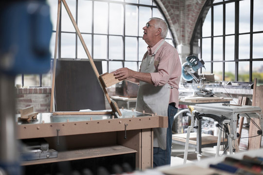 Senior carpenter checking wood on workshop bench