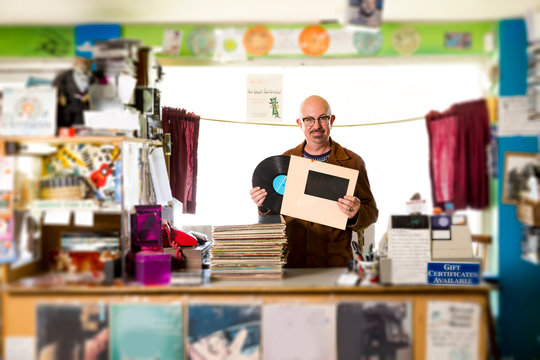 Portrait of mature man in record shop, putting record into record sleeve