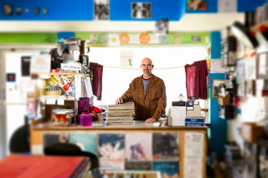 Portrait of mature man in record shop, leaning on stack of records