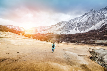 Fototapeta na wymiar Woman with backpack trekking through the yellow dry field
