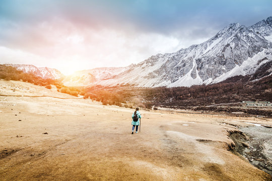 Woman with backpack trekking through the yellow dry field