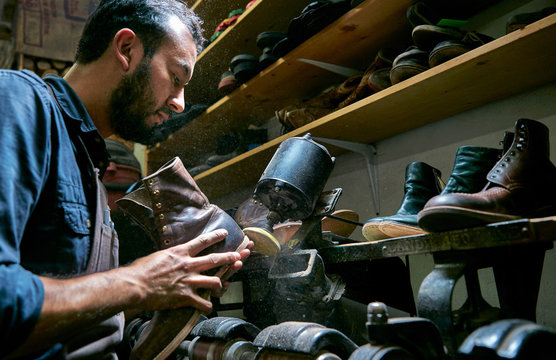 Male cobbler in traditional shoe workshop repairing boot heel