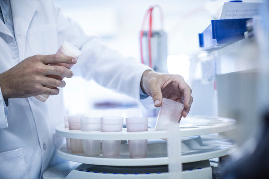 Mid adult man inserting test cups in laboratory