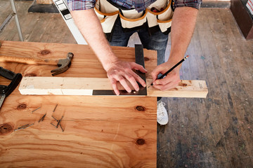 Cropped view of carpenter marking timber using set square