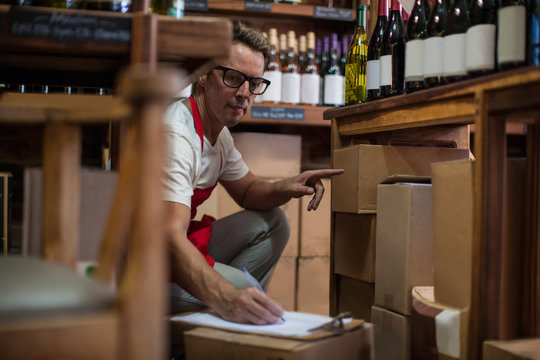 Man in wine shop stock taking bottles of wine