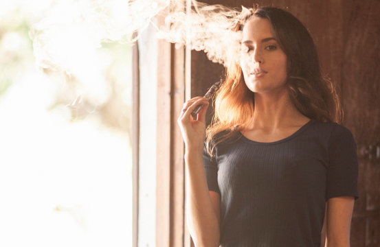 Woman looking at camera vaping