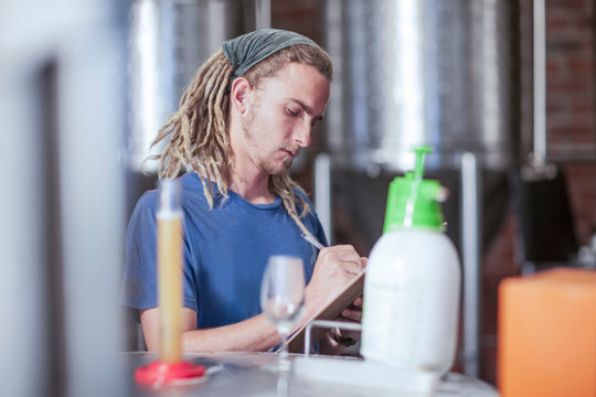 Man in microbrewery quality checking craft beer
