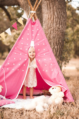 Laughing baby girl playing in wigwam with toys outdoors. Looking at camera. Playful © morrowlight