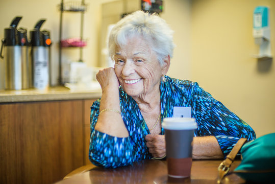 Gray haired woman at table looking at camera smiling