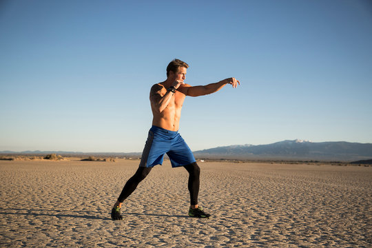Man kickbox training, punching on dry lake bed, El Mirage, California, USA