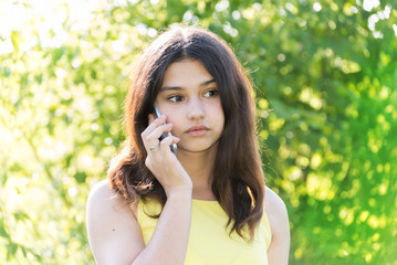 Sad girl talking on phone in park