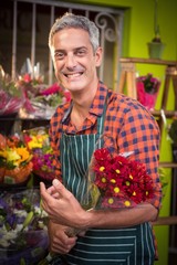 Male florist holding bouquet of flower at his flower shop