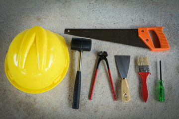 Helmet,paint brush,Plastering trowel, hammer, screwdriver,Cream wire cutters, saws on the cement floor