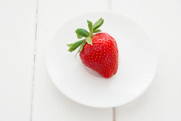 Fresh strawberry in white plate on the white wooden table