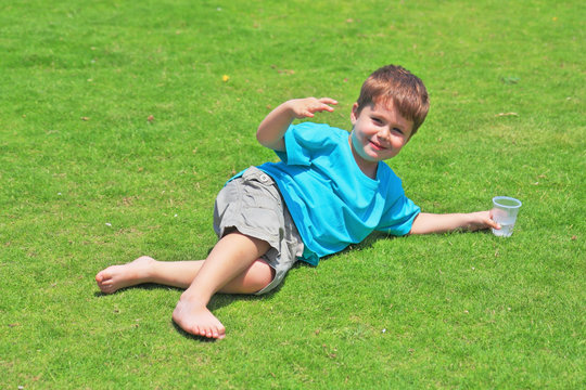 The charming four-year-old boy on a green grassy lawn