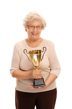 Elderly lady holding a golden trophy