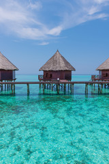 Honeymoon trip. Overwater  bungalows with stair descending into the sea. Turquoise color of the lagoon. Tropical island in the Indian Ocean. Luxury holiday.