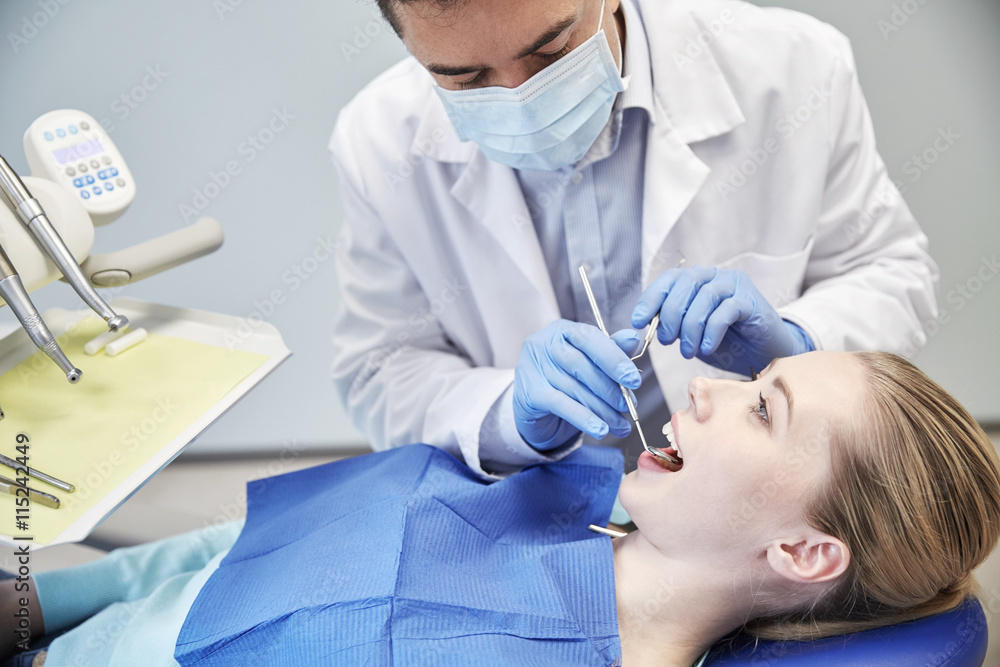 Wall mural male dentist in mask checking female patient teeth