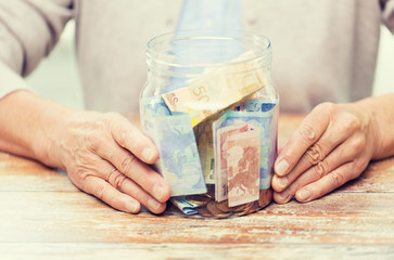 close up of senior woman with money in glass jar