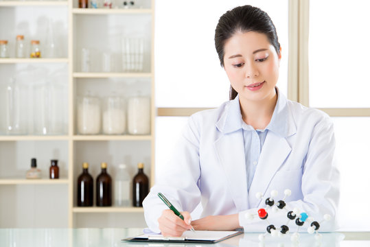 asian female scientist recording Chemical formula on clipboard
