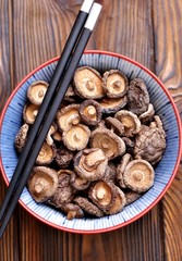 Dried shiitake mushrooms on a wooden background.