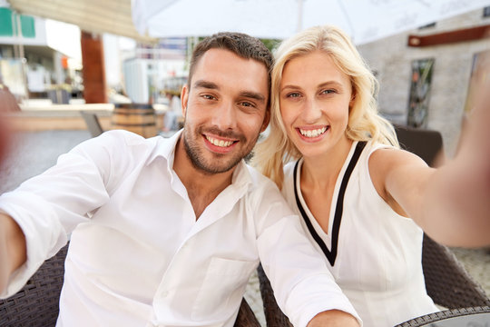 happy couple taking selfie at restaurant terrace