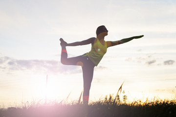 Silhouette young woman practicing yoga at backyard