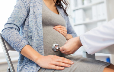 doctor with stethoscope and pregnant woman belly