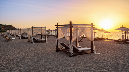 Canopy beds on the sandy beach in a sunrise