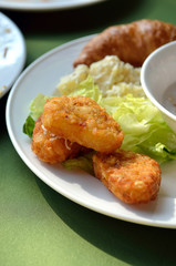 chicken nuggets and vegetable salad on a white plate..