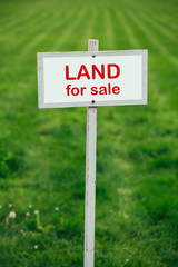 land for sale sign against trimmed lawn background