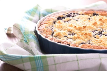 Fresh blueberry pie in blue baking dish on checkered cloth