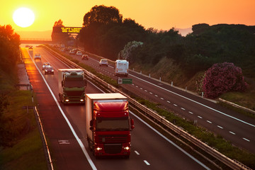trucks in the highway at sunset - obrazy, fototapety, plakaty