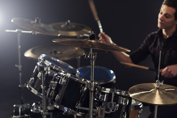 Fototapeta na wymiar Side View Of Young Drummer Playing Drum Kit In Studio