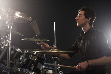 Side View Of Young Drummer Playing Drum Kit In Studio