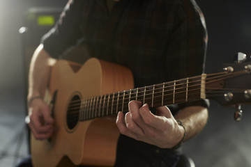 Fototapeta na wymiar Close Up Of Man Playing Acoustic Guitar In Studio